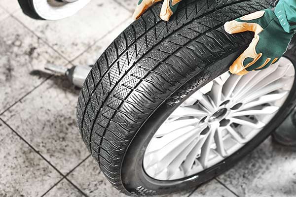 Auto mechanic working in garage and changing wheel alloy tire.