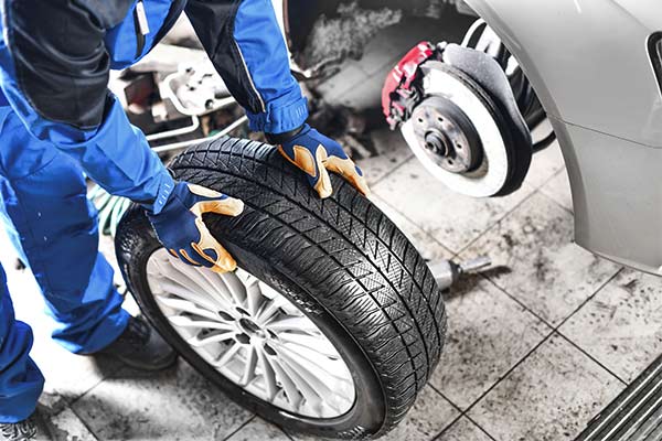 Auto mechanic working in garage and changing wheel alloy tire.